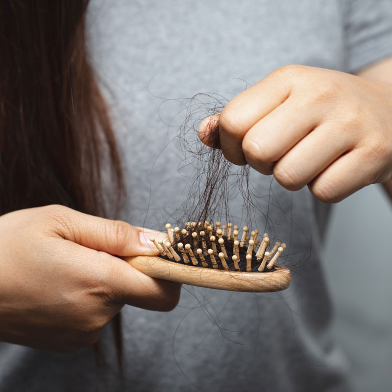 someone pulling shed hair out of a brush to illustrate possible link between hair and hormones